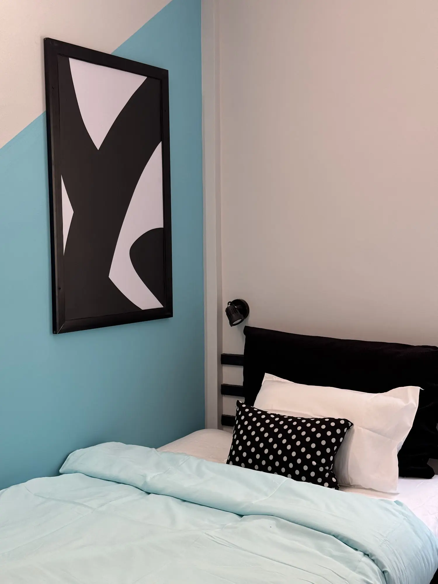 Bed with a teal wall and a black and white print
