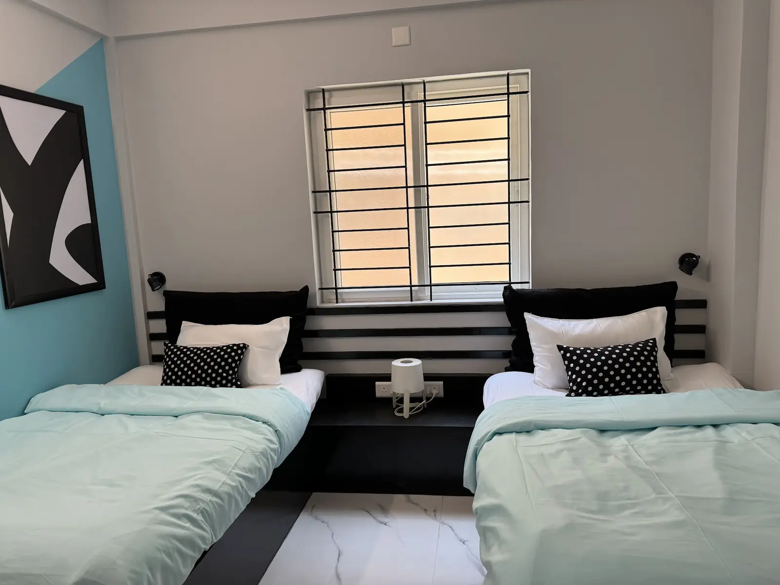 Twin room with a teal wall and an abstract print