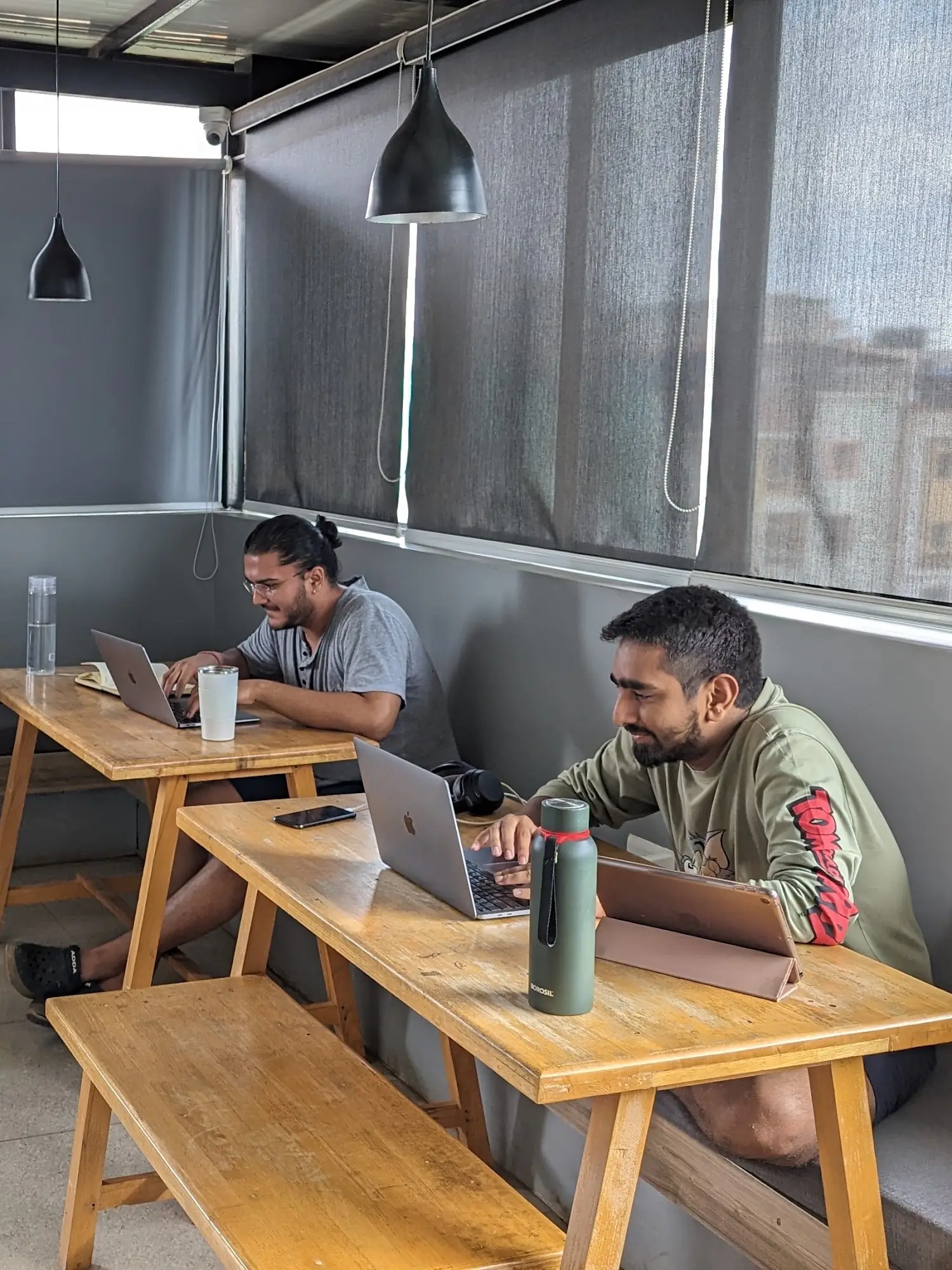 Two residents working on laptops by the window