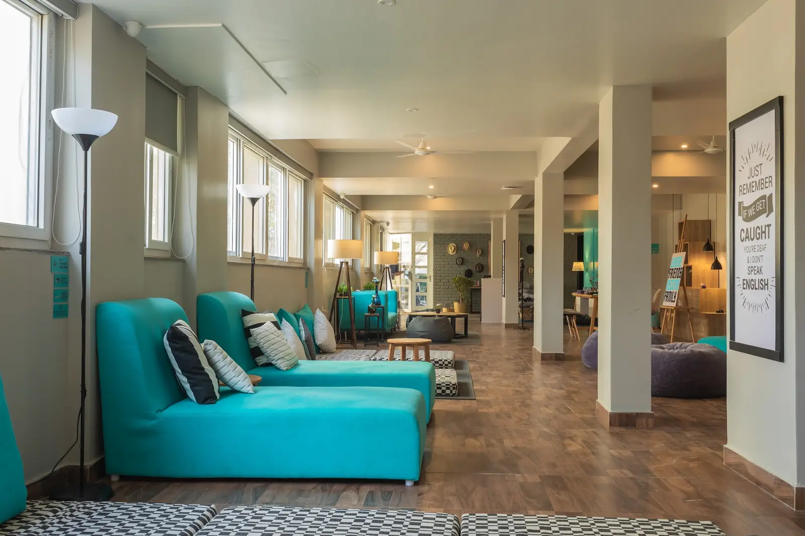 Long lounge with teal sofas and tall windows
