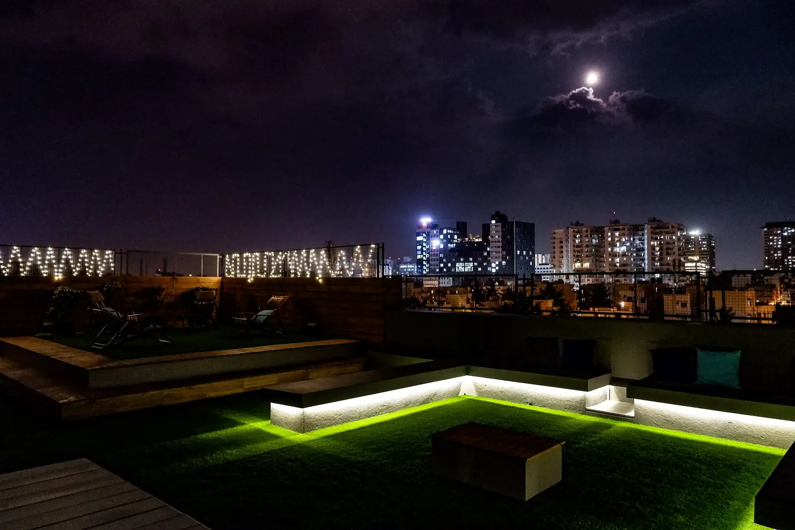 Rooftop lawn lit up at night above the city